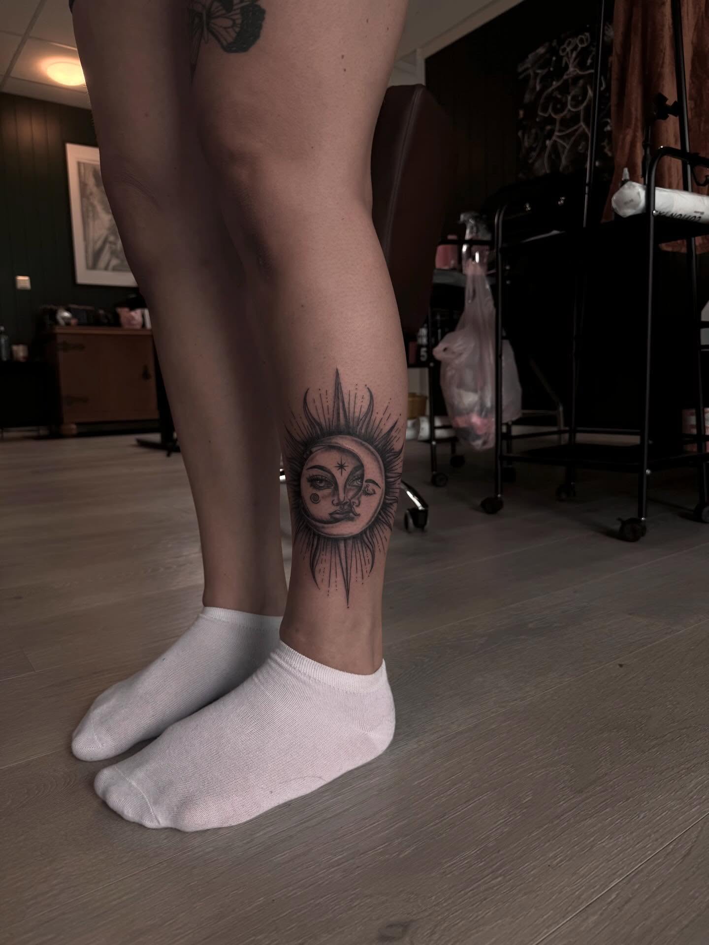 Sol og måne med ansikt, teikna i solkrans på legg